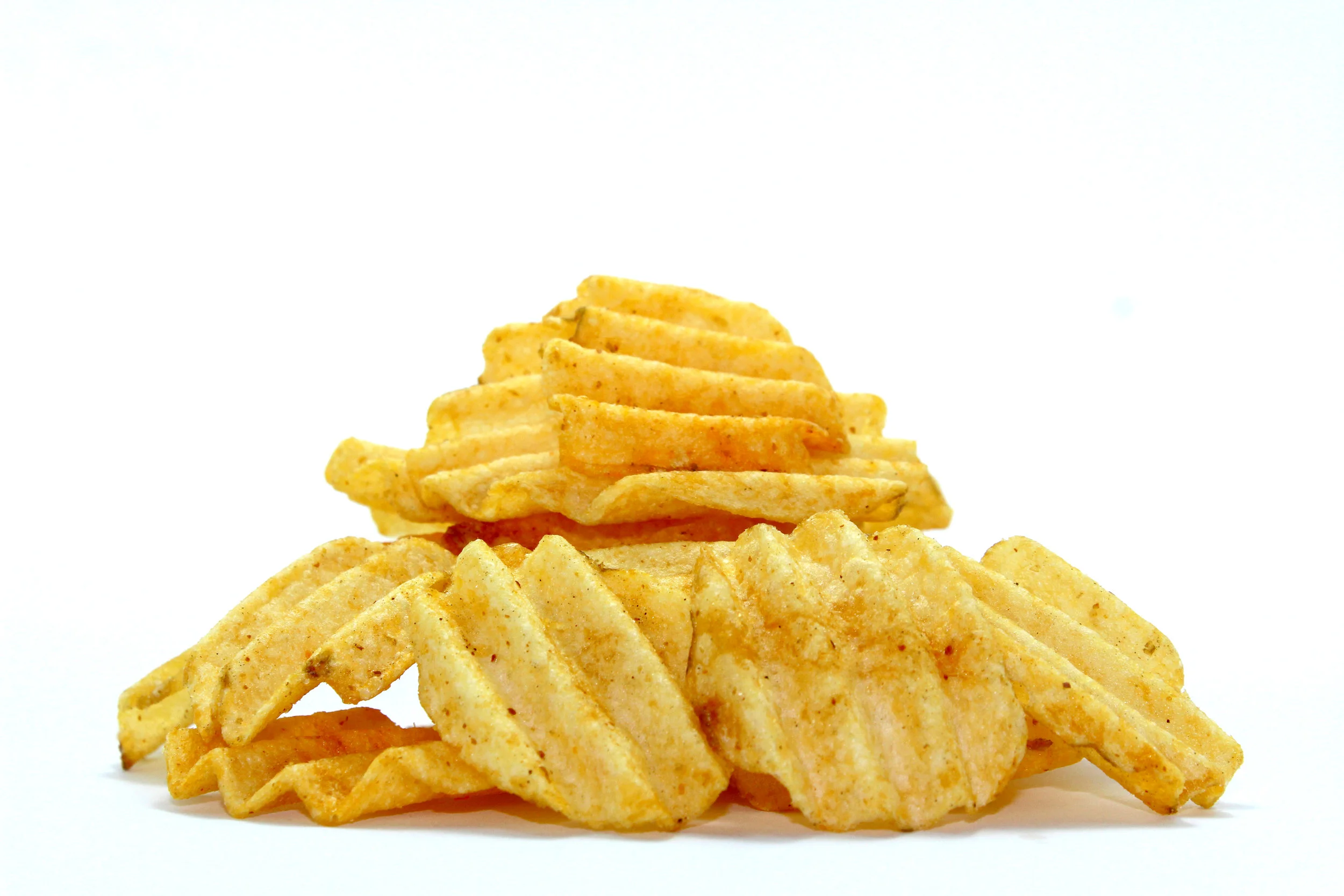 Pile of crinkle-cut potato chips on a plain white background, golden orange tones